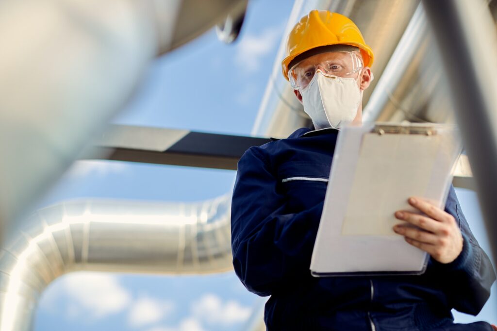 Below view of construction site inspector with face mask taking notes.